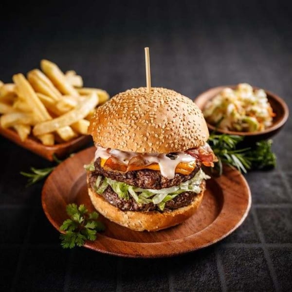 Double cheeseburger with bacon, lettuce, and sauce, served with fries and coleslaw.